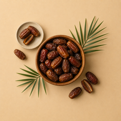 Wooden bowl of whole dates with palm fronds and a small dish of dates on a sand-coloured background